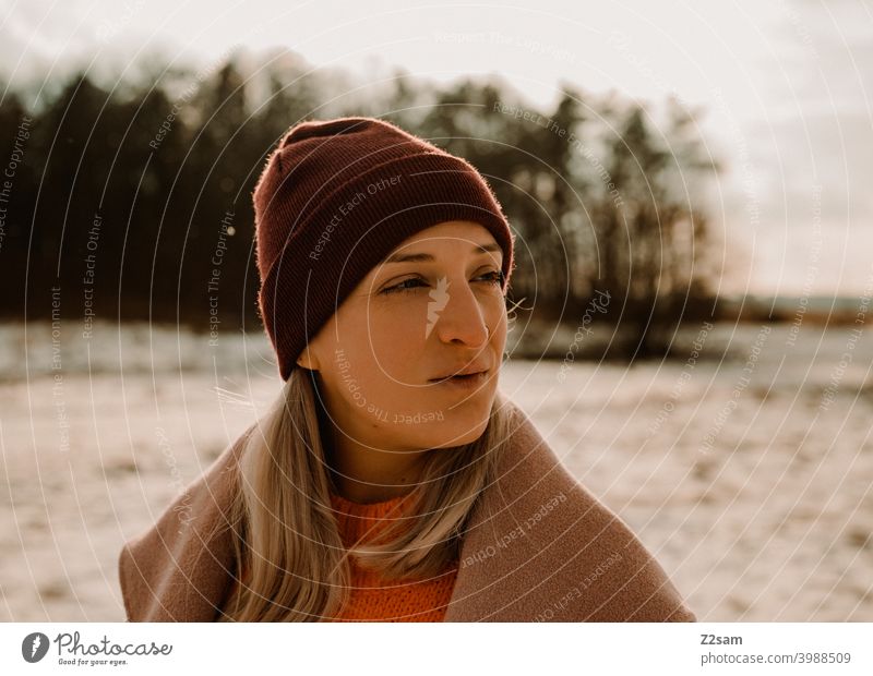 Portrait einer modisch gekleideten Frau in Winterlandschaft winterwonderland frau junge frau mantel spaziergang schnee sonne licht natur schal mütze lange haare