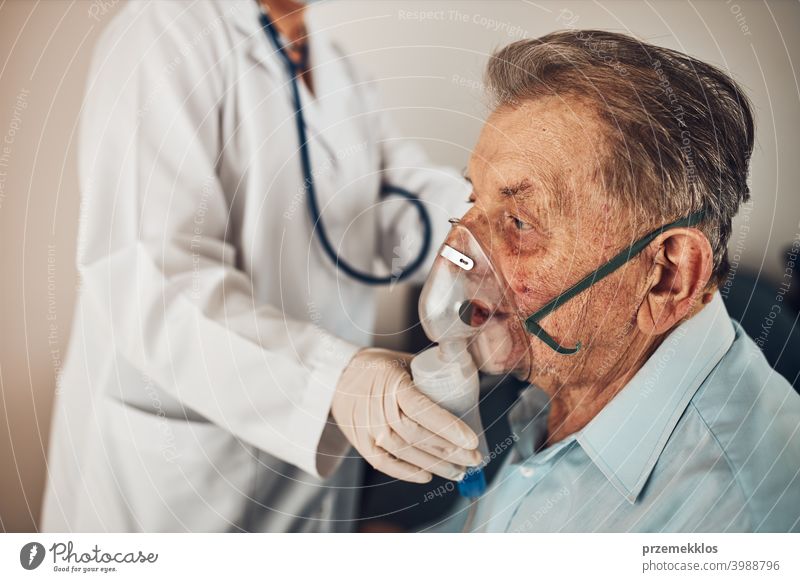 Arzt, der einem älteren Mann, der an einer Lungenkrankheit leidet, ein Medikament während der Inhalation verabreicht. Behandlung von Covid-19 oder Coronavirus