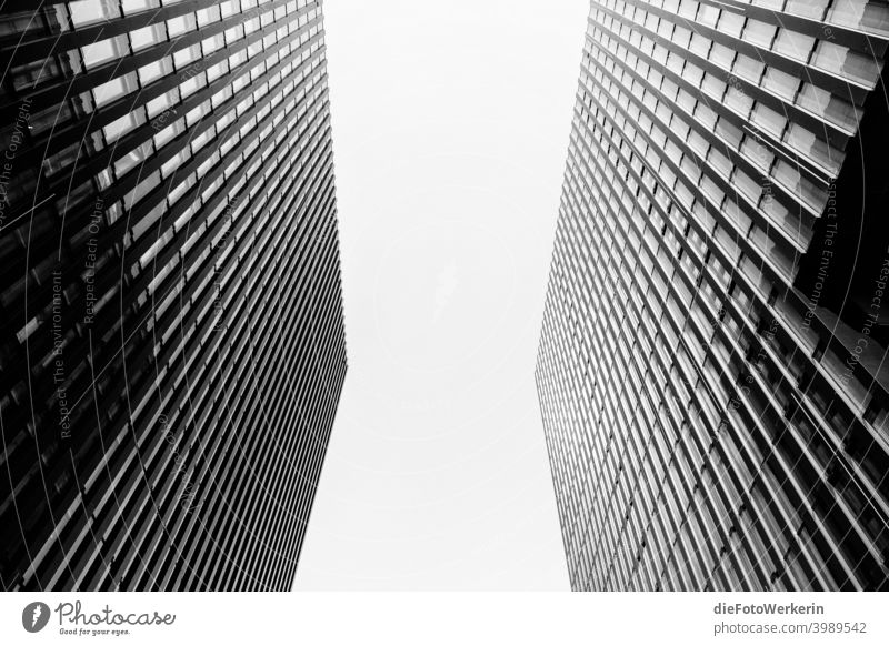 Blick in den Himmel zwischen zwei Hochhäusern Moderne Architektur Draußen Farblos Fluchtlinien Hochhaus Gebäude Kontrastreich Stadt Symmetrie Wolkenkratzer grau