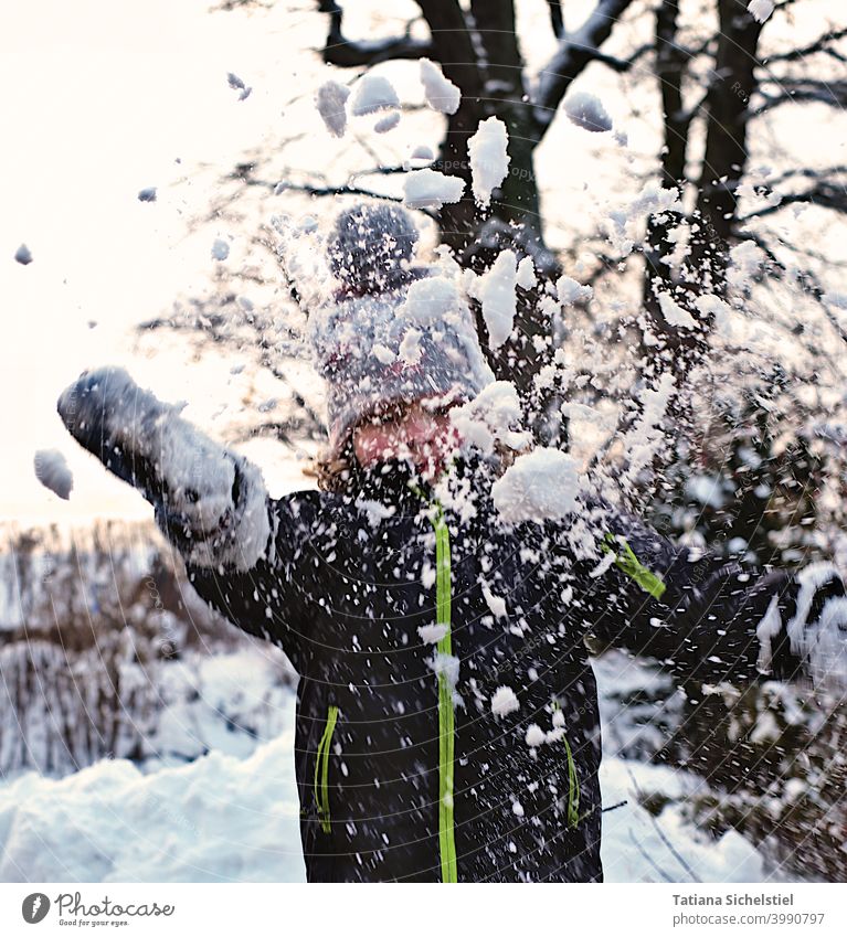Mädchen wirft Schnee in die Luft, Frontalaufnahme mit Bewegungsunschäfe Winter Schneeball werfen Freude weiß kalt spielen Außenaufnahme Aktion