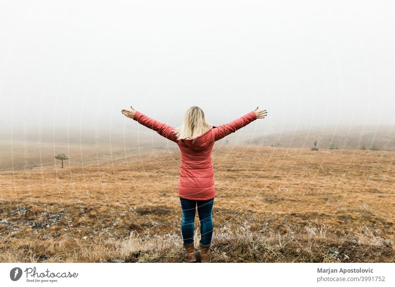 Junge Frau erkundet die Natur an einem nebligen Wintermorgen Abenteuer Herbst Cloud kalt Landschaft Fundstück Erkundung erkunden Entdecker Feld Nebel Freiheit