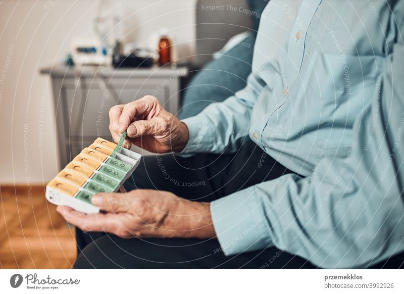 Älterer männlicher Patient beim Öffnen des Tablettenspenders zur Einnahme der nächsten Medikamentendosis. Organisieren von Medikamenten geduldig Person