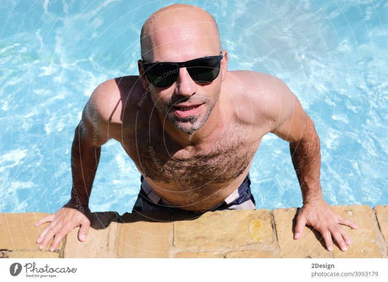 gut aussehend Kerl halb nackt fröhlich Mann lächelnd lachend in blauem Wasser Schwimmbad nass Bräune Schwimmsport Pool kahl Sonnenbrille Sommer jung Glück