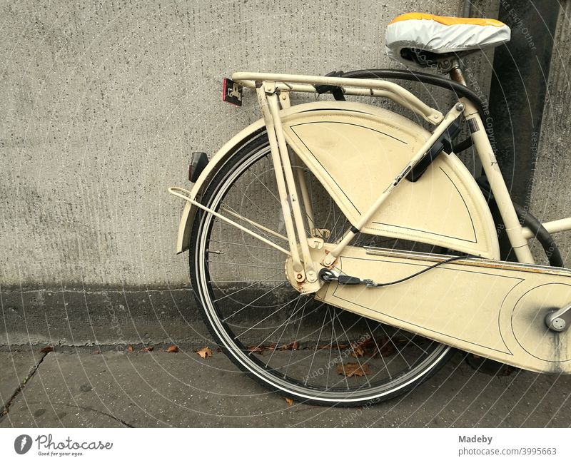 Klassisches Hollandrad in Beige mit Sattelschoner vor farblich passender Hauswand in Köln am Rhein in Nordrhein-Westfalen Rad Fahrrad Damenrad Mantelschutz