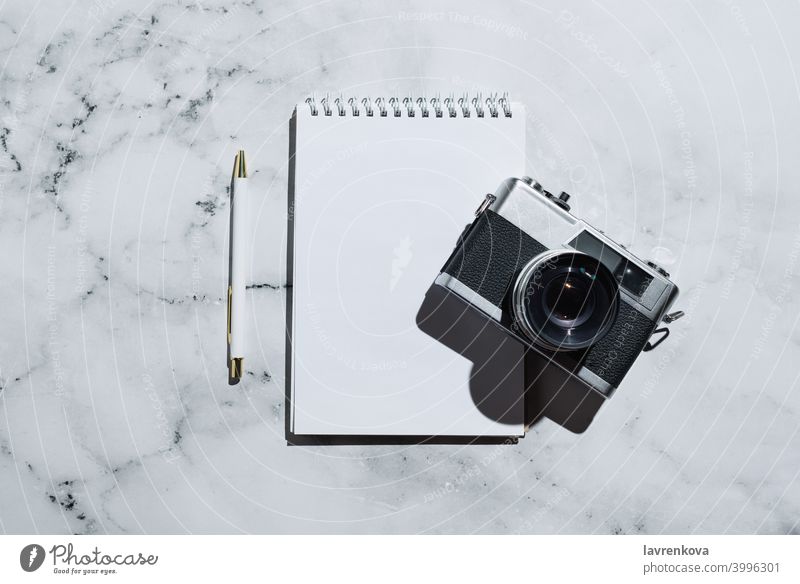 Flatlay von Vintage-Filmkamera und Notizbuch mit Stift auf Marmor Notebook retro Fotokamera Filmmaterial altehrwürdig Draufsicht Business Tisch heimwärts