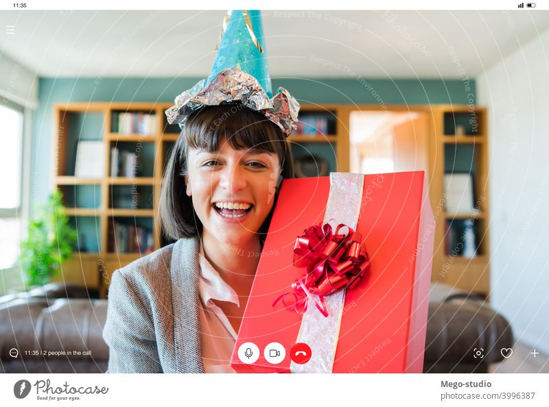 Frau feiert ihren Geburtstag online zu Hause. heimwärts virtuell Feier Mitteilung Internet soziale Distanzierung Anschluss feiern Videoanruf Geschenkverpackung