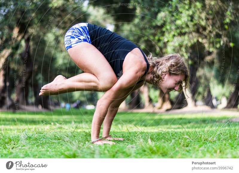 Yoga im Park, mittlere Alter Frau tun bakasana Übung Kranich Pose. Erwachsener Gleichgewicht schön Körper Kaukasier Konzentration Fitness Gras Gesundheit