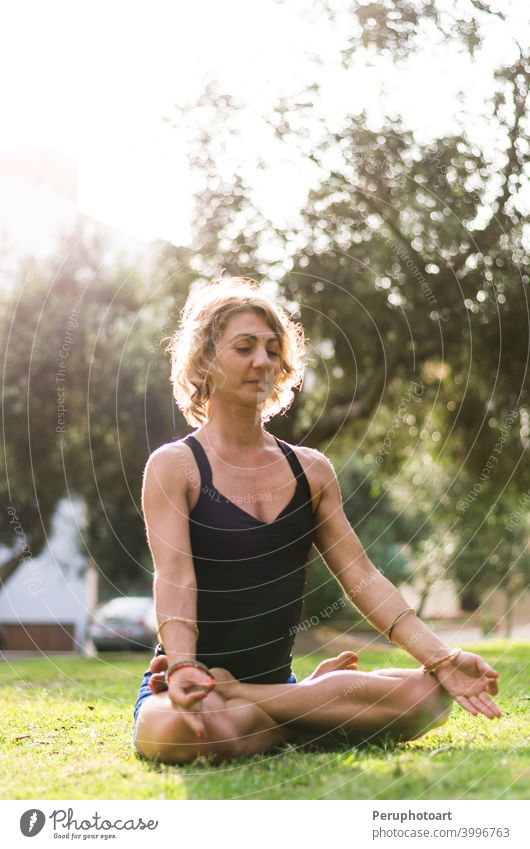 Frau meditiert und übt Yoga, Padmasana. Meditation auf sonnigen Herbsttag im Park. Workout im Freien. Aktivität Asana Übung Mädchen Gesundheit Lifestyle Natur
