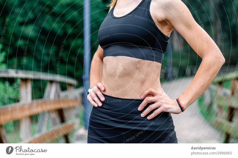 Athletin, die mit Sportbekleidung posiert. Sportlerin Mittelteil Top schlanke flacher Bauch Bauchmuskeln unkenntlich Gesundheit Frau Training Hautflecken Waffen