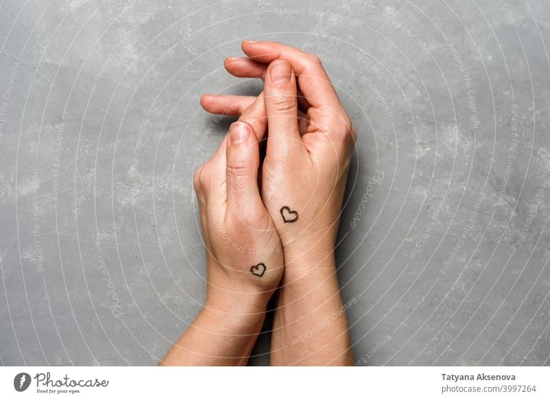 Hände mit Herzen Tattoo auf grau Valentinsgruß Hintergrund Liebe romantisch Feier Feiertag Romantik Symbol Gruß Herzform Beteiligung handpoke Paar