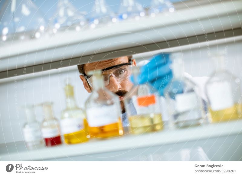 Junger Forscher mit Schutzbrille beim Prüfen von Reagenzgläsern Analyse Analysieren Biochemiker Biochemie Biologie Biotechnologie Kaukasier Chemikalie Chemiker