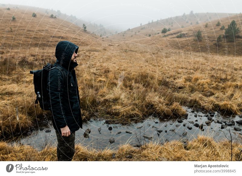 Junger Mann erkundet die Natur an einem nassen Wintermorgen in den Bergen Abenteuer allein Herbst Rucksack Backpacker Herausforderung kalt Erkundung erkunden