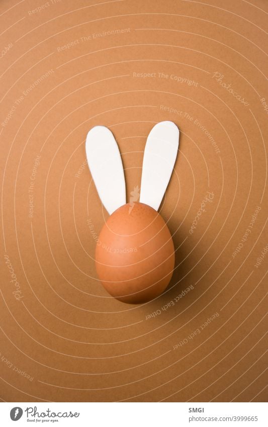 Draufsicht auf ein Ei mit Kaninchenohren, das eine chirurgische Maske trägt. Osterei mit Kaninchenohren Hintergrund Hase feiern Feier christian Christentum