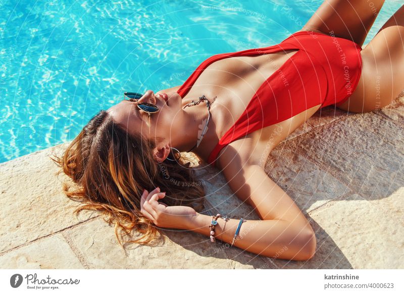 Junge Frau in roten einteiligen Badeanzug entspannen neben einem Schwimmbad tropisch Pool Wasser Sommer jung Kaukasier Mode allein im Freien exotisch sinnlich
