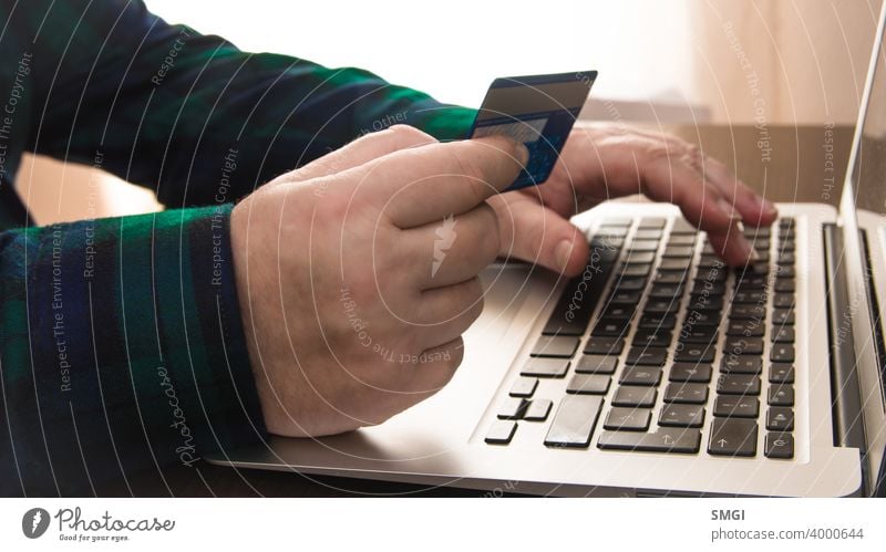 Nahaufnahme von einer Hand, die eine Kreditkarte vor einem Laptop hält. Konzept der Kartenzahlung im Internet. Erwachsener Banking Rechnung kaufen Postkarte