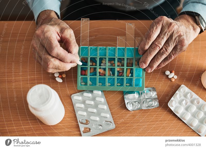 Senior Mann organisiert seine Medikamente in Pillenspender. Senior Mann nimmt Pillen aus Box Tablette Krankheit Spender geduldig Verschreibung medizinisch