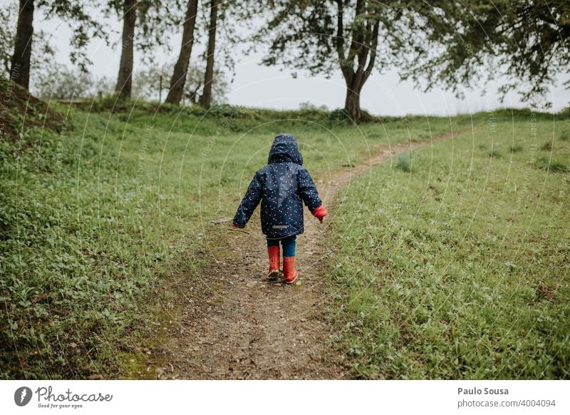 Rückansicht Kind beim Gehen im Park rot Gummistiefel laufen wandern Wälder Wald authentisch Kindheit Spielen Farbfoto Stiefel Herbst Natur Freude Tag Mensch