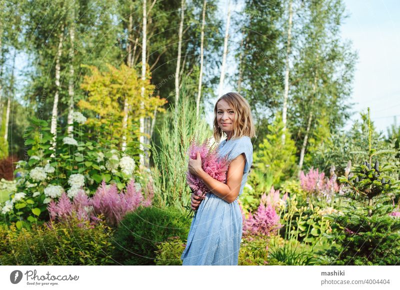 Frau Gärtnerin posiert mit Strauß Astilbe Blumen in privaten Garten. Landleben und Landschaftsgestaltung Konzept Gartenarbeit Pflanze Glück Kaukasier Lifestyle