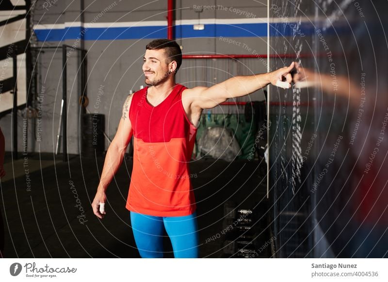 Mann, der auf Trainingspläne zeigt. Crossfit Funktionstraining Übung Gesundheit Sport Fitnessstudio Gebäude bügeln Hanteln Muskel Trainerin Hardcore Aktivität