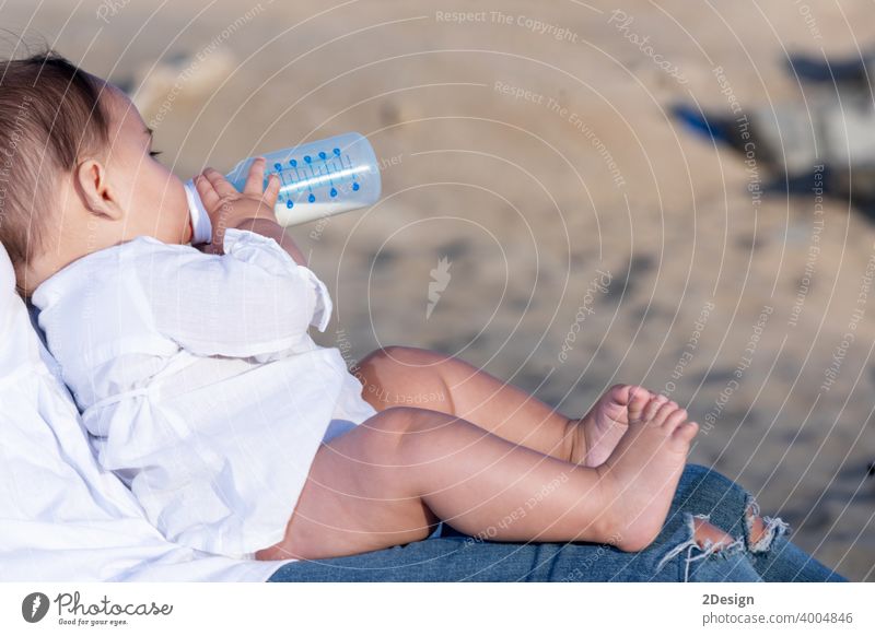 Neugeborenes trinkt Milch aus einer Babyflasche, sitzt auf Mama Beine im Freien neugeboren Flasche melken Kind Säugling Mutter Gesundheit Pflege niedlich Person
