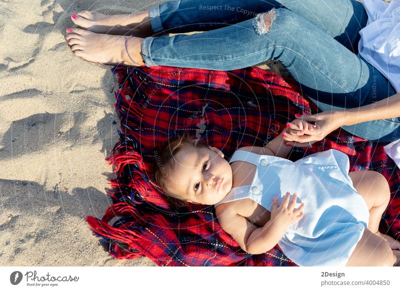 Lächelnde Mutter spielt mit Neugeborenen auf Strandtuch liegend Baby neugeboren Liebe Lügen Familie Fröhlichkeit Frau Person Handtuch Lachen Sand Sonnenlicht
