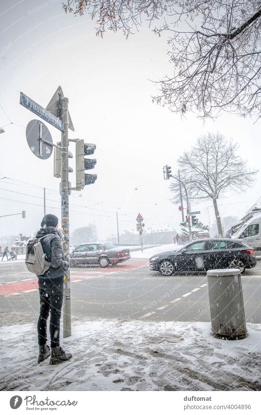 Mann wartet bei Schneegestöber an befahrener Kreuzung Winter weiß urban Stadt schneien frieren Eis kalt Schneefall Schneeflocke Ampel Verkehr Außenaufnahme