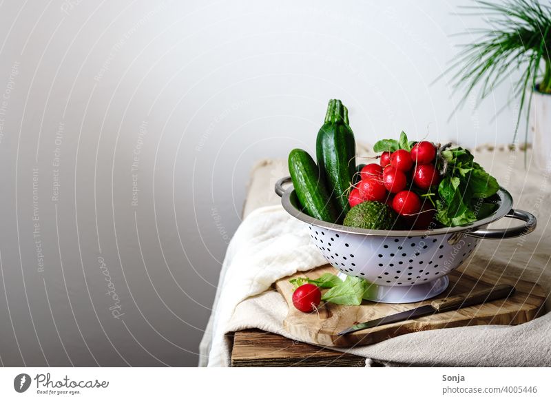 Rohe Radieschen und grünes Gemüse in einem Sieb auf einem Küchentisch roh Stillleben ländlich Vegetarische Ernährung Gesunde Ernährung Bioprodukte Diät