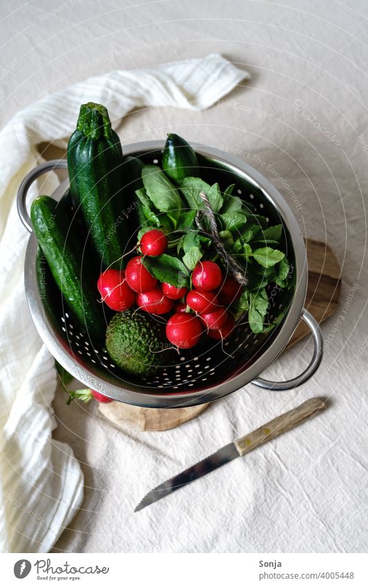 Radieschen und grünes Gemüse in einem Sieb auf einem beigen Leinen Tischtuch roh tischtuch Gesundheit Lebensmittel Vegetarische Ernährung organisch frisch Diät