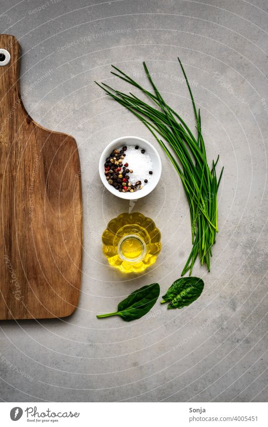 Frische Kräuter, Olivenöl, Salz und ein leeres Holzschneidebrett auf einem rustikalen Tisch Kräuter & Gewürze Schneidebrett Zutaten Lebensmittel roh frisch