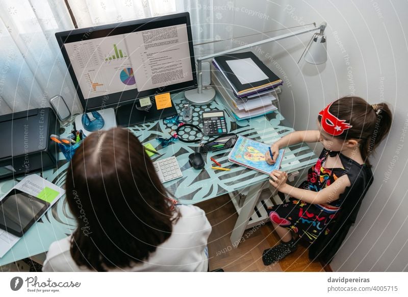 Frau bei Telearbeit mit ihrer Tochter beim Zeichnen Overhead Coronavirus covid-19 Quarantäne Einsperrung Computer Draufsicht Vereinbarkeit von Familienarbeit
