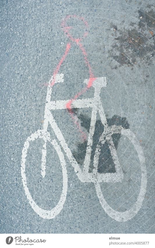 Ein Spaßvogel hat mit roter Farbe ein Strichmännchen auf ein weißes Fahrrad - Piktogramm auf der grauen, asphaltierten Straße gemalt / Straßenmarkierung Humor