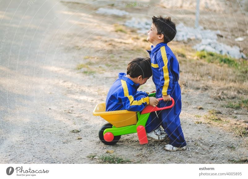 Fröhliche und lächelnde Kinder haben Spaß auf dem Feld mit einer Schubkarre Brüder Geschwister Zwillinge Glück Lächeln Freundschaft elementar primär Babys
