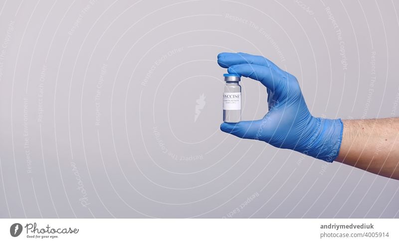 Entwicklung und Schaffung eines Coronavirus-Impfstoffs COVID-19 .Coronavirus-Impfstoff in Glasflasche in der Hand des Arztes auf grauem Hintergrund. Impfstoff Konzept des Kampfes gegen Coronavirus.