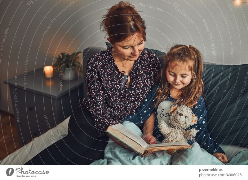 Mutter lesen Buch ihre Tochter im Bett vor dem Schlafengehen. Gutenachtgeschichten für Kind Nacht Schlafenszeit Familie heimwärts Literatur Frau Schlafzimmer