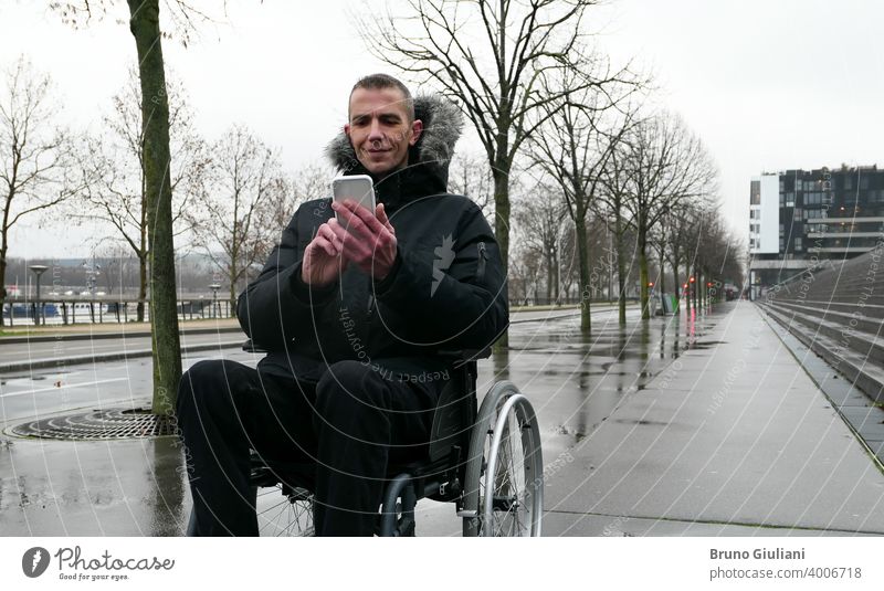 Konzept der behinderten Person. Mann in einem Rollstuhl draußen auf der Straße vor der Treppe. Menschen mit Technologie mit Smartphone. deaktiviert Behinderung