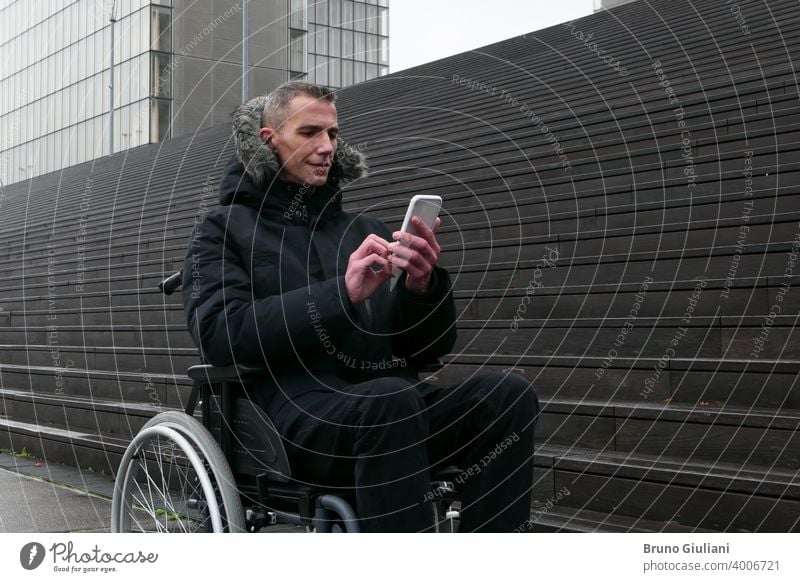 Konzept der behinderten Person. Mann in einem Rollstuhl draußen auf der Straße vor der Treppe. Menschen mit Technologie mit Smartphone. deaktiviert Behinderung