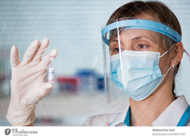 Ärztin mit OP-Maske und in Handschuhen hält Impfstoffampulle und Spritze. Impfung während der COVID-19-Pandemie Arme Pflege Klinik Coronavirus covid-19 Kur