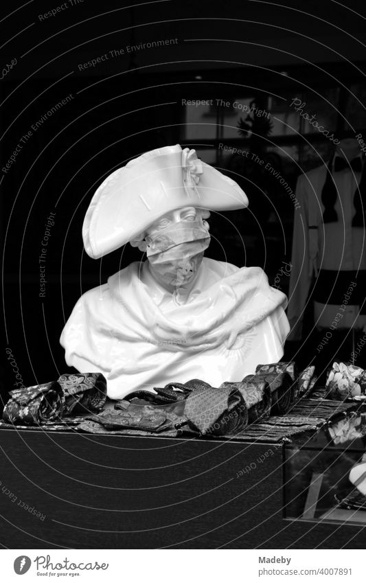 Büste Friedrich des Großen mit Mundschutz vor dem Geschäft eines Herrenausstatter in den Hackeschen Höfen am Hackeschen Markt in der Hauptstadt Berlin, fotografiert in neorealistischem Schwarzweiß