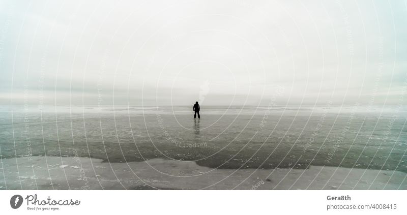 Silhouette eines einsamen Mannes auf Eis im gefrorenen Meer Hintergrund Strand Klima Wolken wolkig Küste Küstenlinie kalt Tag dreckig Frost gefrorenes Meer