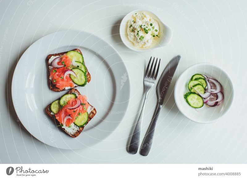 leckeres gesundes Frühstück - Lachs und Avocado-Toast mit Frischkäse, Gurke und rote Zwiebel auf weißem Hintergrund Lebensmittel Belegtes Brot Zuprosten Snack