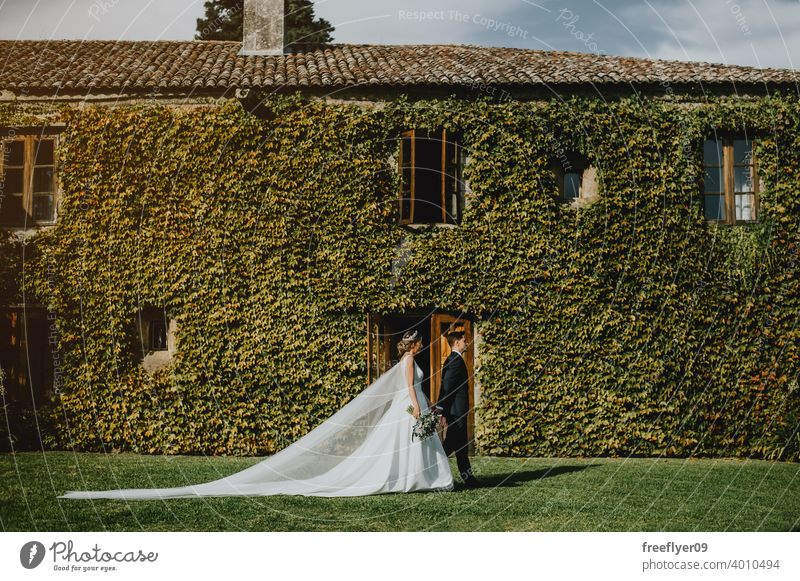 Ehepaar am Hochzeitstag vor einer Wand voller Kletterpflanzen Heirat Engagement Braut Menschen jung attraktiv Textfreiraum pazo Galicia antik Burg oder Schloss