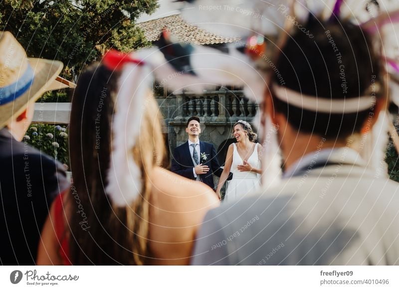 Paar lachend bei einer Hochzeit mit verkleideten Gästen Heirat Engagement Braut Menschen jung attraktiv Textfreiraum Party Spaß 20s genießend Grimasse