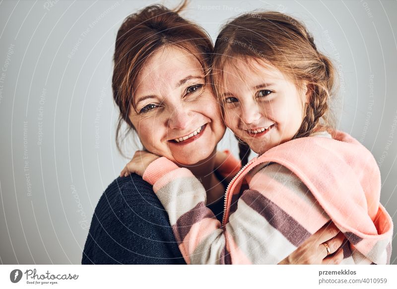 Glückliche Mutter und Tochter umarmt, umarmt und lächelnd zusammen. Familienporträt. Glücklicher Moment. Frau und kleines Mädchen posieren zur Kamera Person