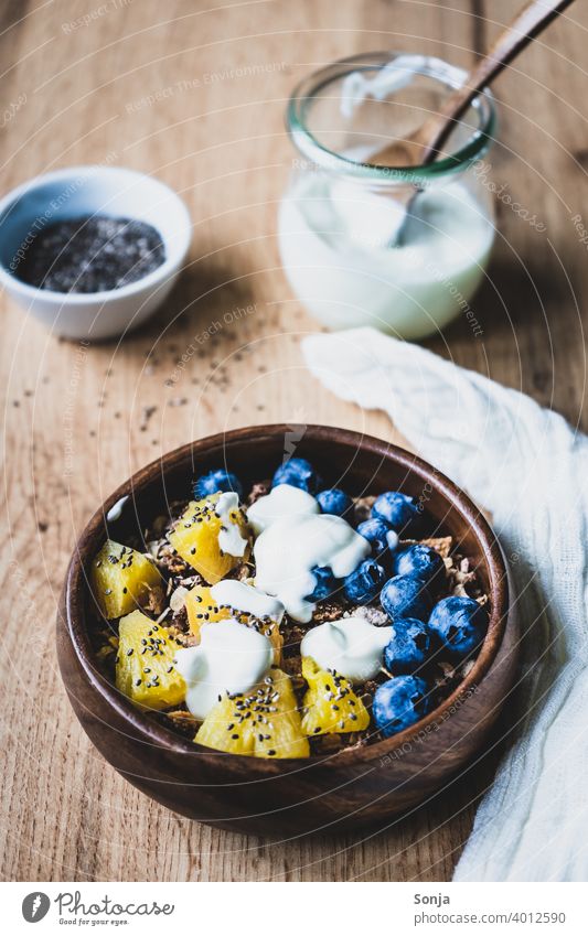Müsli mit Joghurt, Heidelbeeren und Ananas in einer Holz Schüssel Frühstück gesund rustikal chiasamen Löffel Diät süß Getreide Haferflocken Gesundheit Dessert