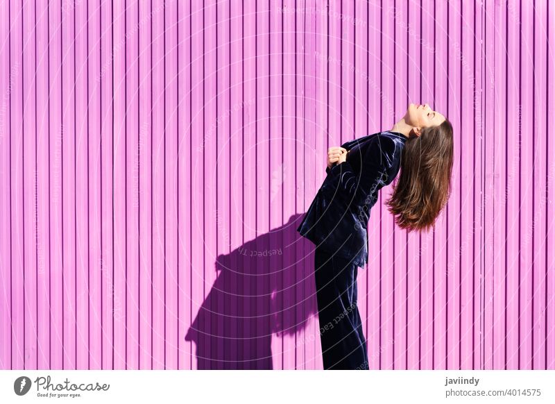 Frau in blauem Anzug posiert in der Nähe eines rosa Rollladens. Frisur Behaarung Mode Model Gebäude blind Fuchsie purpur bewegend Mädchen Person Lifestyle urban
