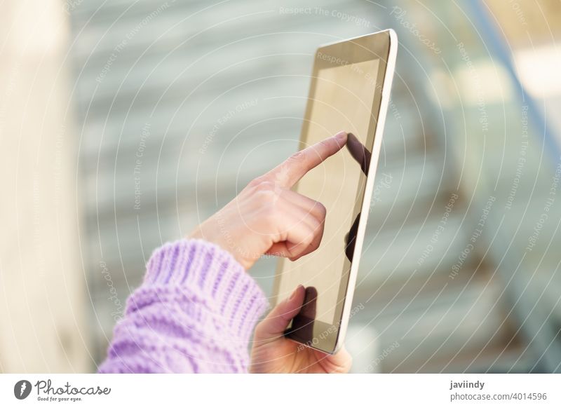 Detail einer nicht erkennbaren Frau, die im Freien ein digitales Tablet benutzt. Tablette Gerät unkenntlich Schüler Mädchen Winter Verschlussdeckel Rucksack