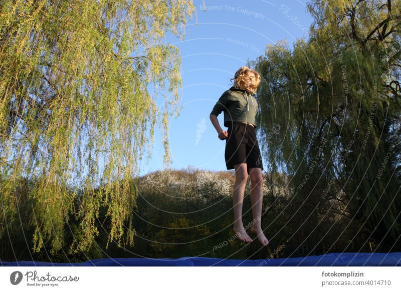 Teenager hüpft auf einem Trampolin hüpfen springen beweglich Lebensfreude Bewegung Jugendliche Körperbeherrschung Aktion aktivität sich spüren lebendig