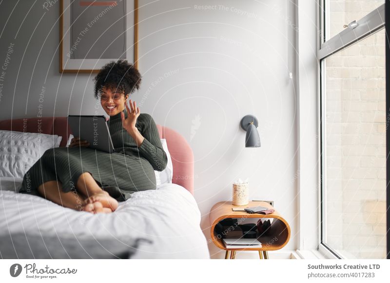 Frau liegend auf Bett zu Hause machen Videoanruf auf digitalen Tablet digitales Tablett Tablet Computer Video-Chat Mitteilung winkend Familie Freunde Sperrung