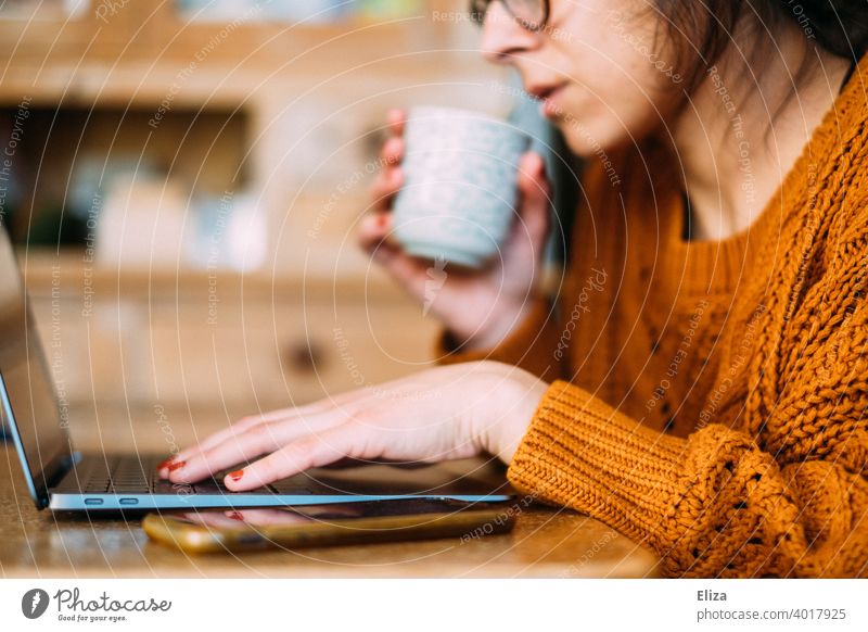 Eine Frau sitzt mit Kaffee und Laptop Zuhause am Tisch und arbeitet im Home Office Homeoffice zuhause arbeiten Kaffeetasse Notebook Computer Arbeitsplatz