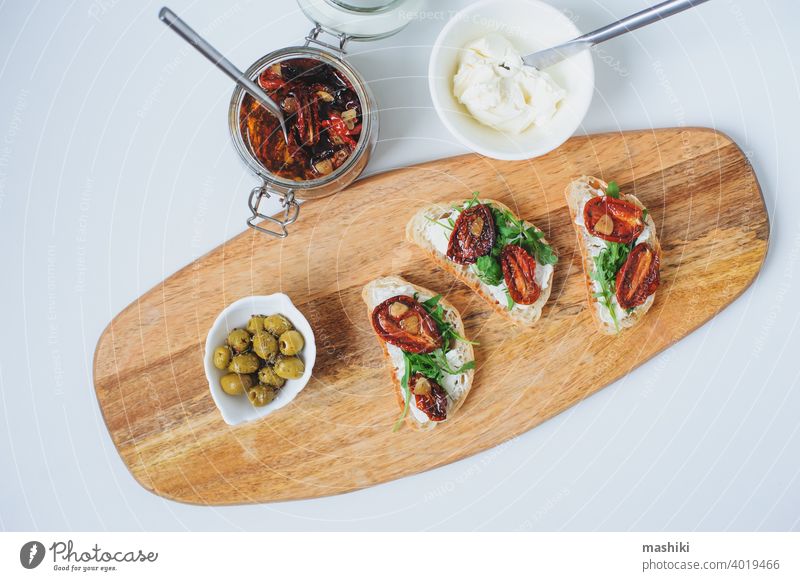 traditionelle italienische Bruschetta - Brottoast mit sonnengetrockneten Tomaten, Frischkäse, Olivenöl und Rucola. Belegtes Brot Lebensmittel Zuprosten Snack